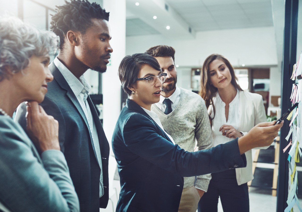 Shot of a group of focused businesspeople having a discussion while making use of a glass white board to go through notes