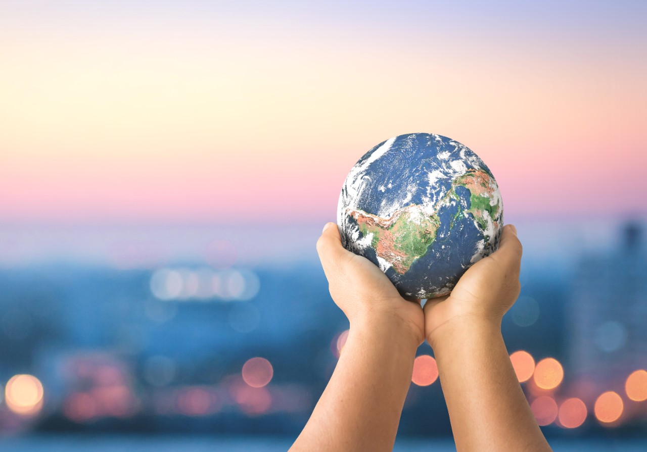 Human hands holding earth global over blurred city night background. Elements of this image furnished by NASA